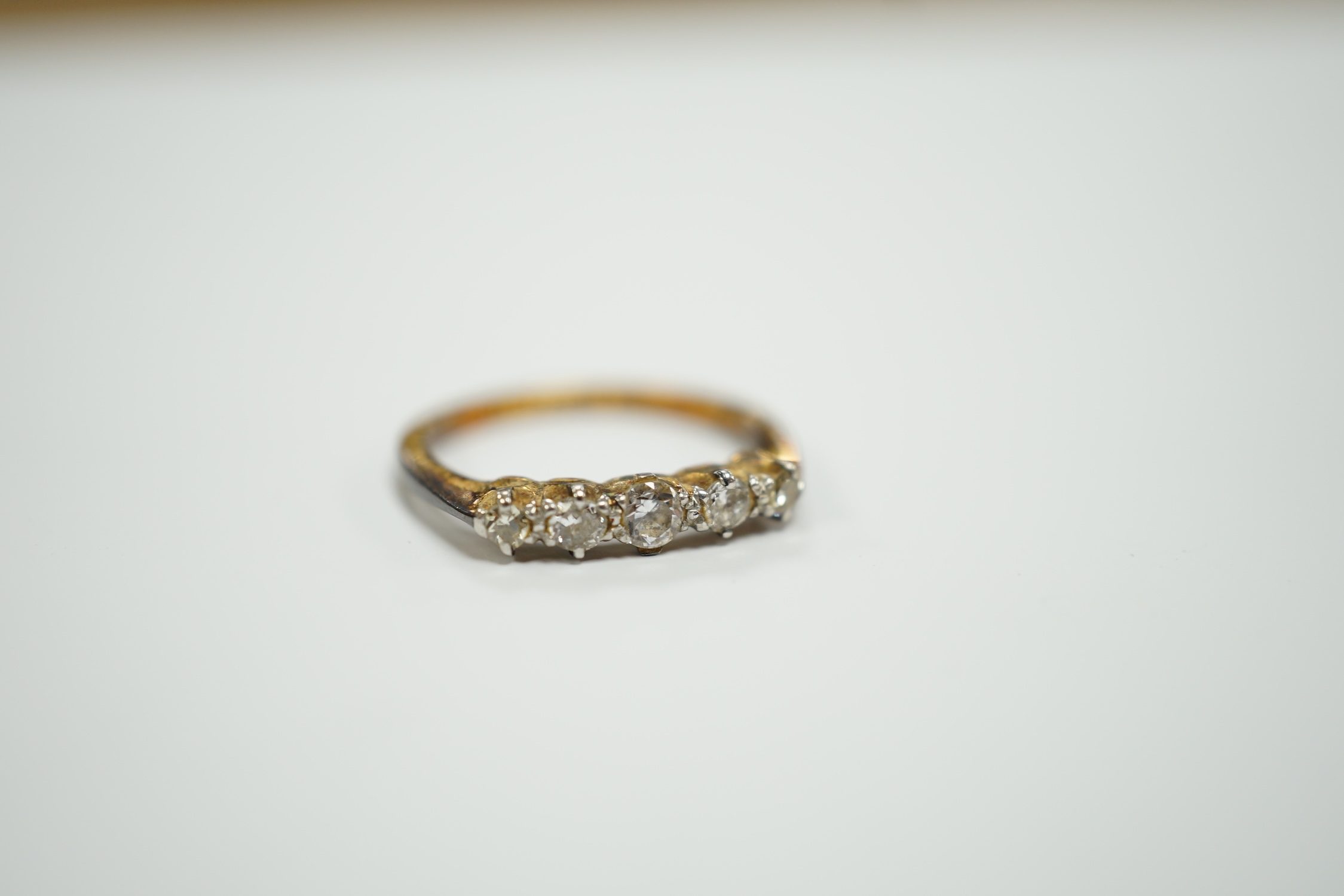 An early 20th century 18ct, plat and graduated five stone diamond chip set half hoop ring, size H, gross weight 2.2 grams.